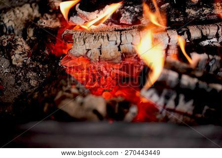 Burning Coals In The Barbecue On A Blurred Background, The Texture Of The Flame