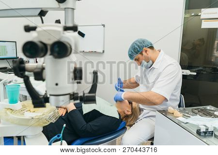 Doctor Used Microscope. Dentist Is Treating Patient In Modern Dental Office. Operation Is Carried Ou