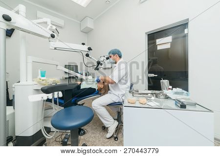 Doctor Used Microscope. Dentist Is Treating Patient In Modern Dental Office. Operation Is Carried Ou