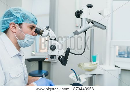 Doctor Used Microscope. Dentist Is Treating Patient In Modern Dental Office. Operation Is Carried Ou