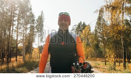 Training An Athlete On The Roller Skaters. Biathlon Ride On The Roller Skis With Ski Poles, In The H