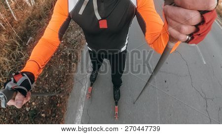 Training An Athlete On The Roller Skaters. Biathlon Ride On The Roller Skis With Ski Poles, In The H
