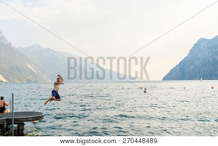 Handsome Funny Attractive Man Having Fun Jumping Into The Water In Lago Di Garda In Italy In Summer 