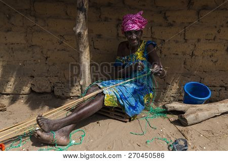 Orango Island, Guinea-bissau - February 3, 2018: An Old Woman Working In Front Of Her Hut At The Vil