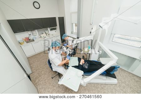 Doctor Used Microscope. Dentist Is Treating Patient In Modern Dental Office. Operation Is Carried Ou