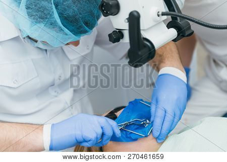 Doctor Used Microscope. Dentist Is Treating Patient In Modern Dental Office. Operation Is Carried Ou