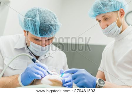 Doctor Used Microscope. Dentist Is Treating Patient In Modern Dental Office. Operation Is Carried Ou