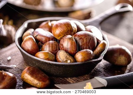 Roasted Chestnuts Served In A Special Perforated Chestnut Pan On An Old Wooden Table.