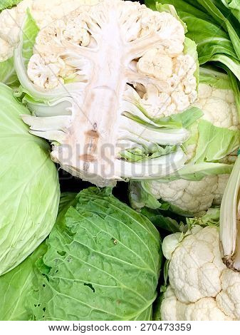A Close Up Of Fresh Cauliflowers Cut In Two And Entire. The Intense Green Colour Od The Leaves In Co