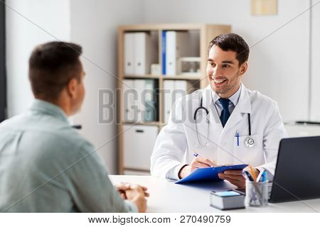 medicine, healthcare and people concept - doctor with clipboard talking to male patient at medical office in hospital