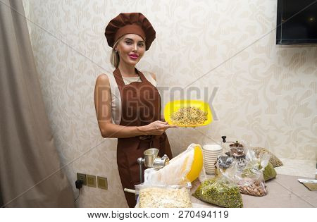 Young Beautiful Woman In An Apron Making Cake With Cream And Berries At The Kitchen