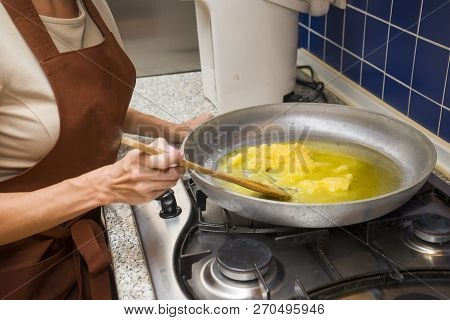 Young Beautiful Woman In An Apron Making Cake With Cream And Berries At The Kitchen