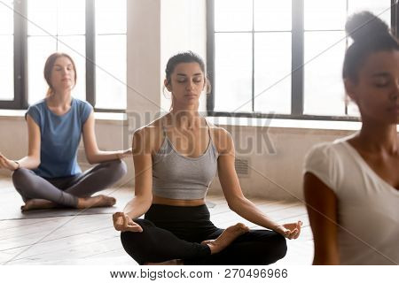 Group Of Young Women Practicing Yoga, Half Lotus Pose