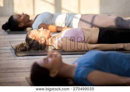 Group Of Attractive Women Practicing Yoga In Dead Body Pose