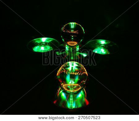 The Image Features A Combination Of Green And Orange On The Reflective Discs And Lensballs.