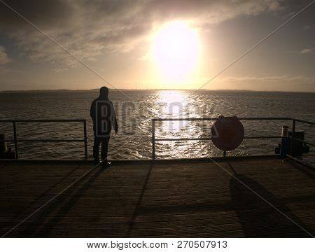 Old Man Watch The Morning Sea Over Pier Handrail.  Man On The Sea Bridge Looking At The Baltic Sea I