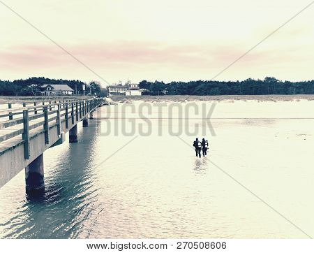 Prerow Germany - January 25 2018: Couple Of Sea Divers Walk From Sea To Beach. End Of Diving Lesson.