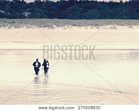 Prerow Germany - January 25 2018: Couple Of Sea Divers Walk From Sea To Beach. End Of Diving Lesson.