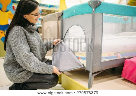 Pregnant woman buying cot in store
