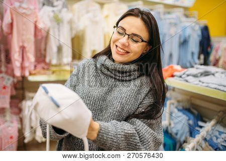 Smiling future mother chooses baby hat