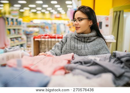 Future mother in glasses buys childrens clothes