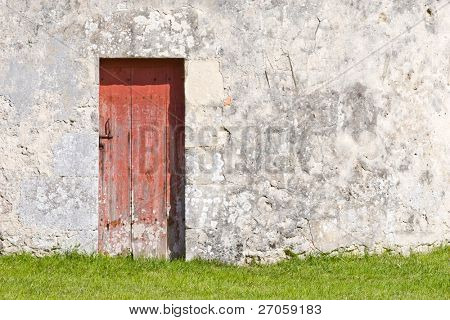 alte rote Holztür auf einer Steinmauer und grünem Gras, Montaigne Burg, Frankreich