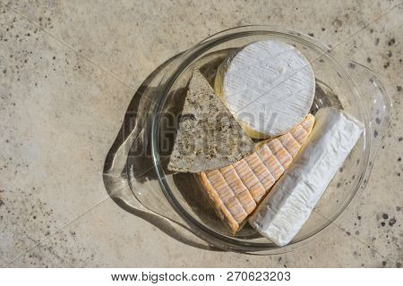 Assorted Various Types Of Delicious Cheese In Glass Plate On Stone Table. Top View.