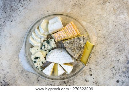 Assorted Various Types Of Delicious Cheese In Glass Plate On Stone Table. Top View.