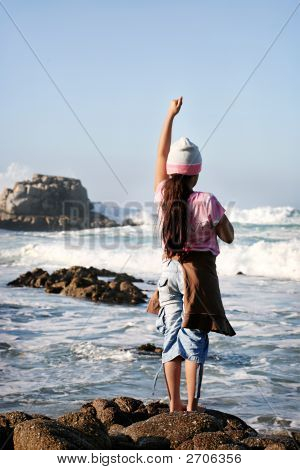 Niña en la orilla rocosa