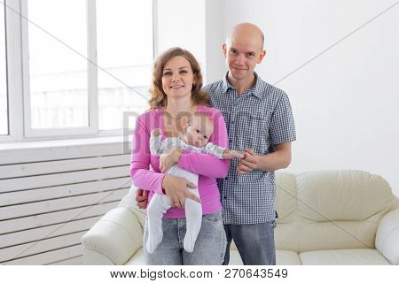 Family, Childhood And Parenthood Concept - Father, Mother Holding Cute Baby Indoors