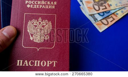 Hands Holding Passports On Blue Background. Citizenship Of Estonia And Russia. Citizenship Of Europe