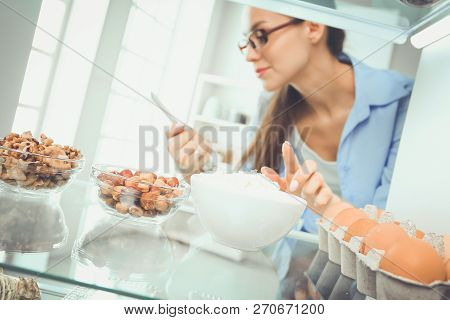 Portrait Of Female Standing Near Open Fridge Full Of Healthy Food, Vegetables And Fruits. Portrait O