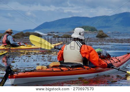 Checkaklis Island, British Columbia, July 20, 2018: Kayakers In Colorful Gear Rest In The Leeward Si