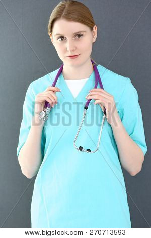 Doctor Woman Portrait With Stethoscope. Young Female Surgeon Or Nurse  Standing Near Grey Wall  In C