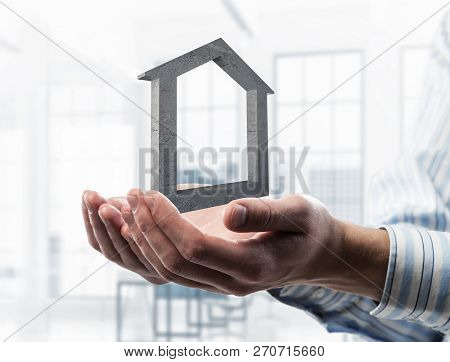 Cropped Image Of Businessman In Suit Keeping Stone House Symbol In Hands. Mixed Media