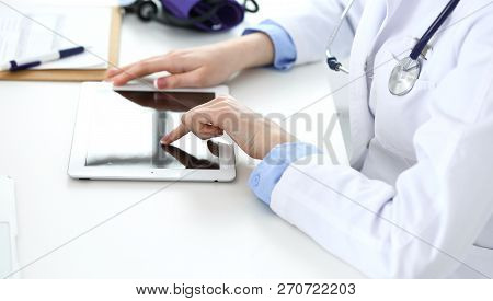 Woman Doctor Using Tablet Computer While Sitting In Hospital Office Closeup. Healthcare, Insurance A