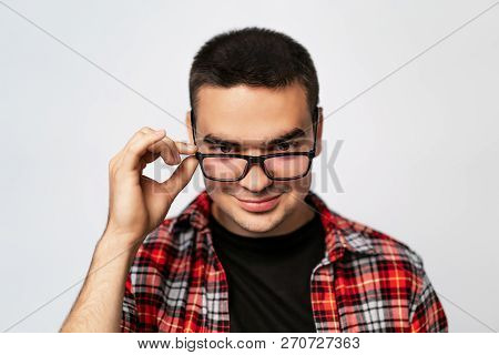 Close-up Of Young Trendy Guy With Glasses Smiling, White Studio Shot. A Portrait Of Clever Man In T-