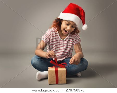 Little Black Girl Oppening Gift Box, Wearing Sants Hat, Studio Shot