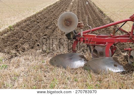 A Vintage Plough With Freshly Cut Earth Furrows.