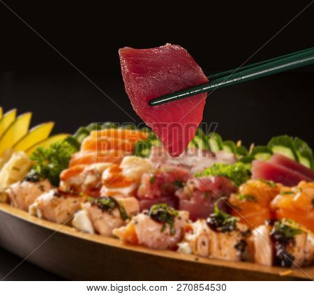 Close Up Tuna Fish In Hashi With Japanese Food Combo Defocused In Black Background.