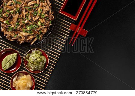 Shimeji Mushrooms In Iron Pan With Ginger, Wasabi And Sunomono In A Black Background.top View.