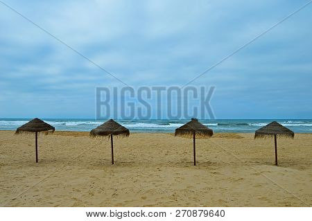 Exotic Umbrellas On Beach Praia De Odeceixe In South Portugal On The Blue Sky Background