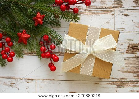 Festive Christmas Background.gift Box With White Bow And Fir Branches With Red Berries And Stars On 