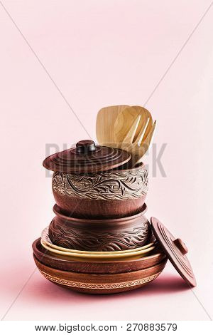 Pots And Plates Of Clay On A White Table And A Pink  Background. Clay Pottery Kitchen Utensils Made