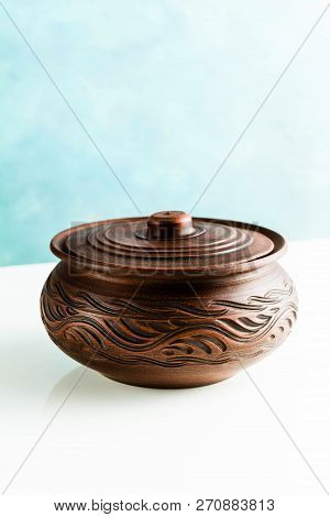 Pots And Plates Of Clay On A White Table And A Blue Background. Clay Pottery Kitchen Utensils Made B