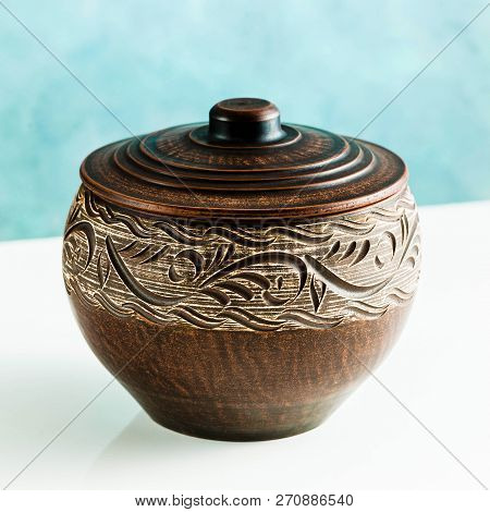 Pots And Plates Of Clay On A White Table And A Blue Background. Clay Pottery Kitchen Utensils Made B