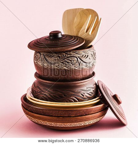 Pots And Plates Of Clay On A White Table And A Pink  Background. Clay Pottery Kitchen Utensils Made