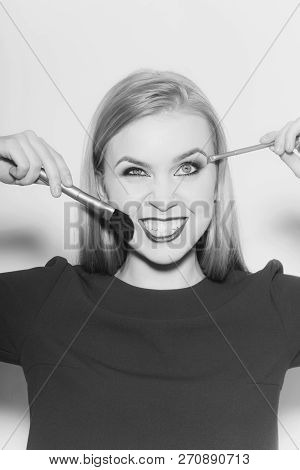 Girl Winking And Smiling With Makeup Brushes. Funny Woman With Long Blond Hair In Blue Dress On Whit