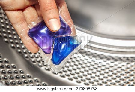 blue gel caps in hand for washing mashine, liquid coloured detergent