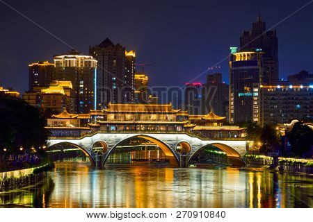 Famous landmark of Chengdu - Anshun bridge over Jin River illuminated at night with modern skyscrapers in background, Chengdu, Sichuan , China